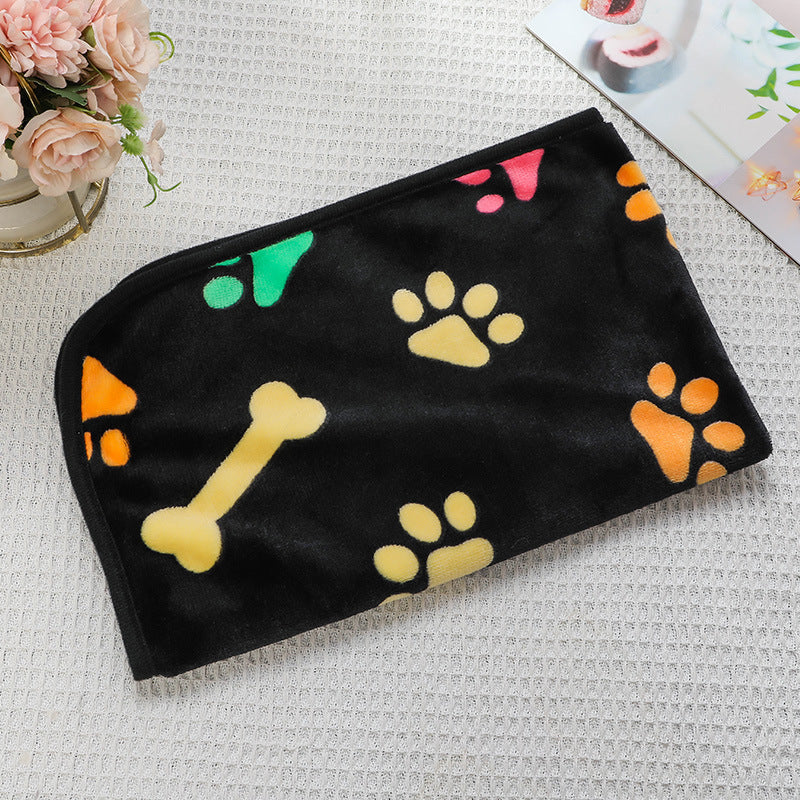 Black towel with colorful paw prints and bones on a textured surface.