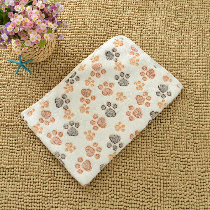 Floral arrangement next to a folded blanket with paw print pattern on a textured surface