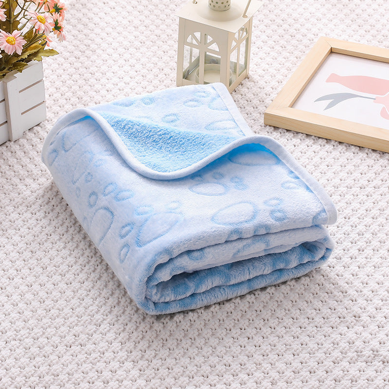 Folded blue blanket on a white carpet with a small table and picture frame in the background.