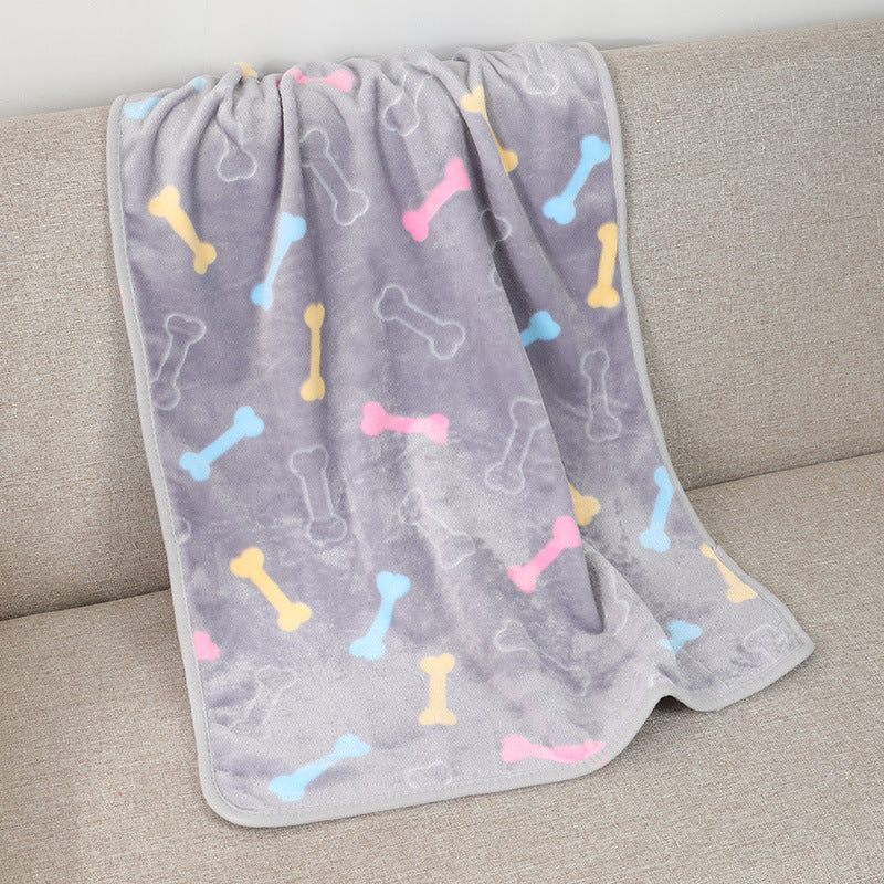 Gray blanket with colorful bone patterns draped over a beige couch.