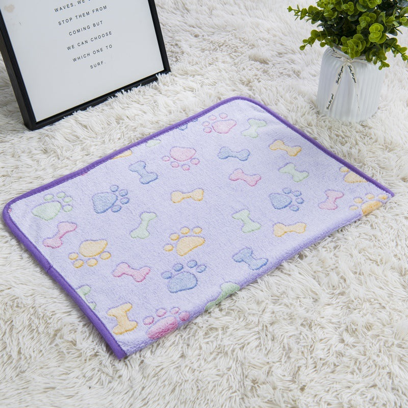 Pastel-colored pet mat with paw and bone patterns on a white carpet.