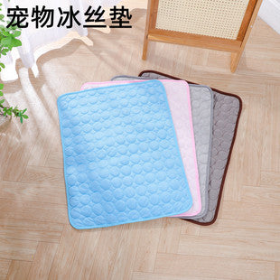 Pet cooling pad in blue and gray on a wooden floor with a plant in the corner.