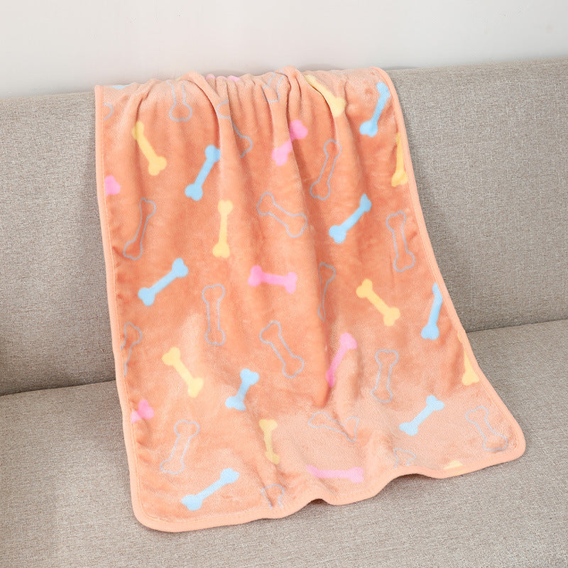 Pink blanket with colorful bone patterns draped over a gray couch.