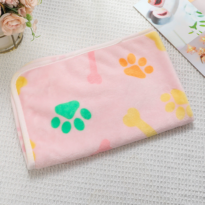 Pink blanket with colorful paw prints on a textured surface
