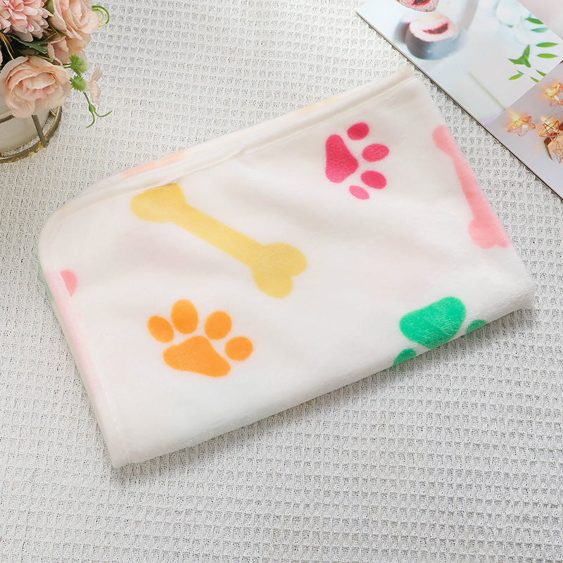 White blanket with colorful paw prints and a bone on a textured surface.