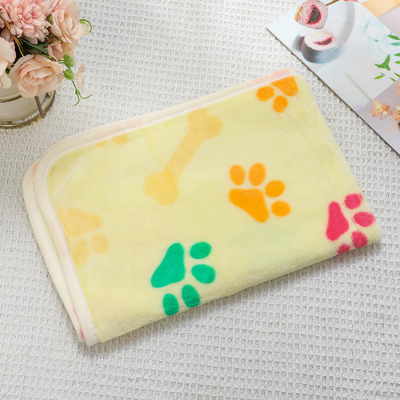 Yellow blanket with colorful paw prints on a textured surface