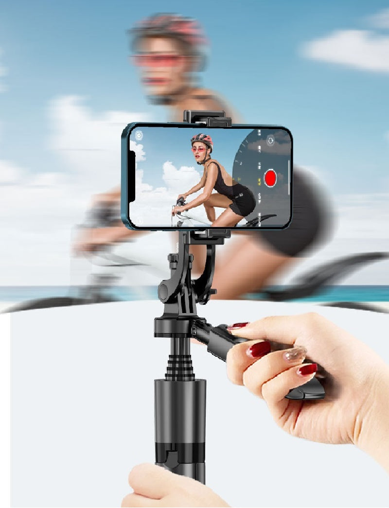Hand holding a smartphone with a gimbal stabilizer, recording a person on a bike.