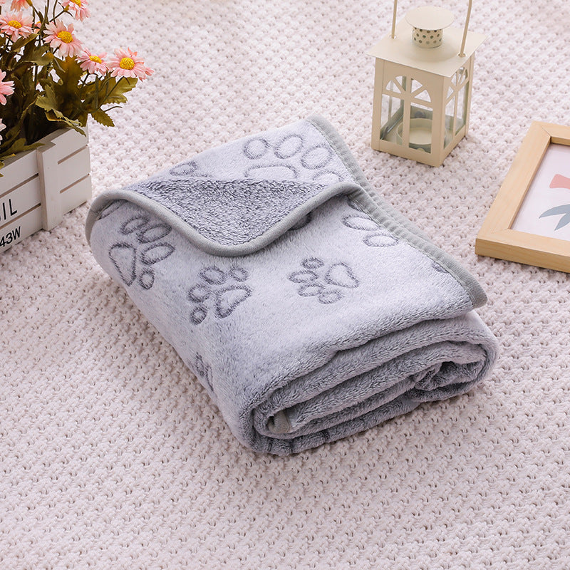 Folded gray towel with paw prints on a light pink carpet