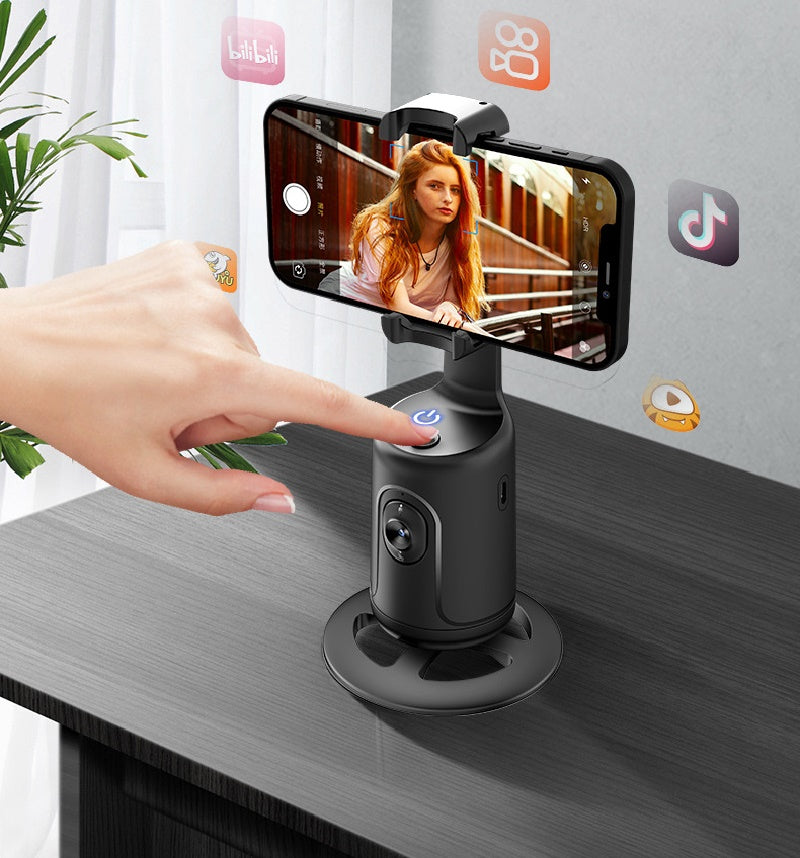 Hand using a smartphone with a phone holder on a table, with social media app icons in the background.